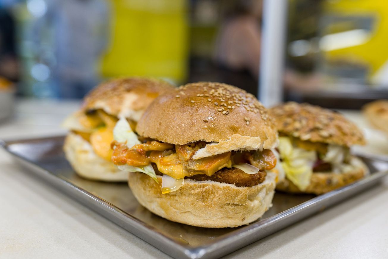 Tre panini per la colazione su un vassoio, con i panini dorati e il ripieno fuso su un tavolo.