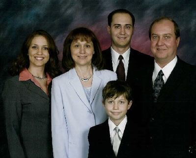 Formal family portrait of five people in suits and dresses against a studio backdrop
