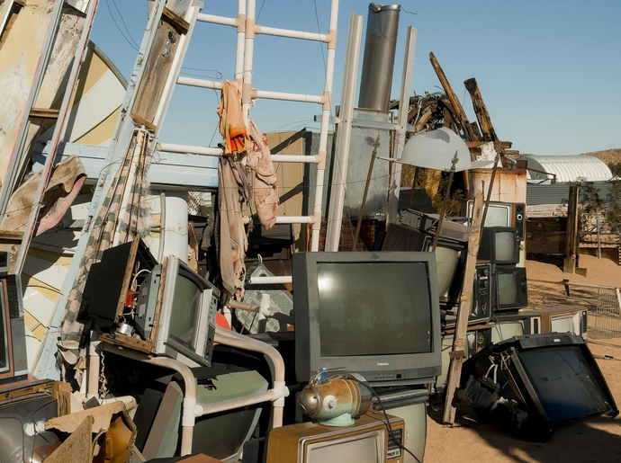 Pile of old electronics and scrap metal outdoors under a clear sky