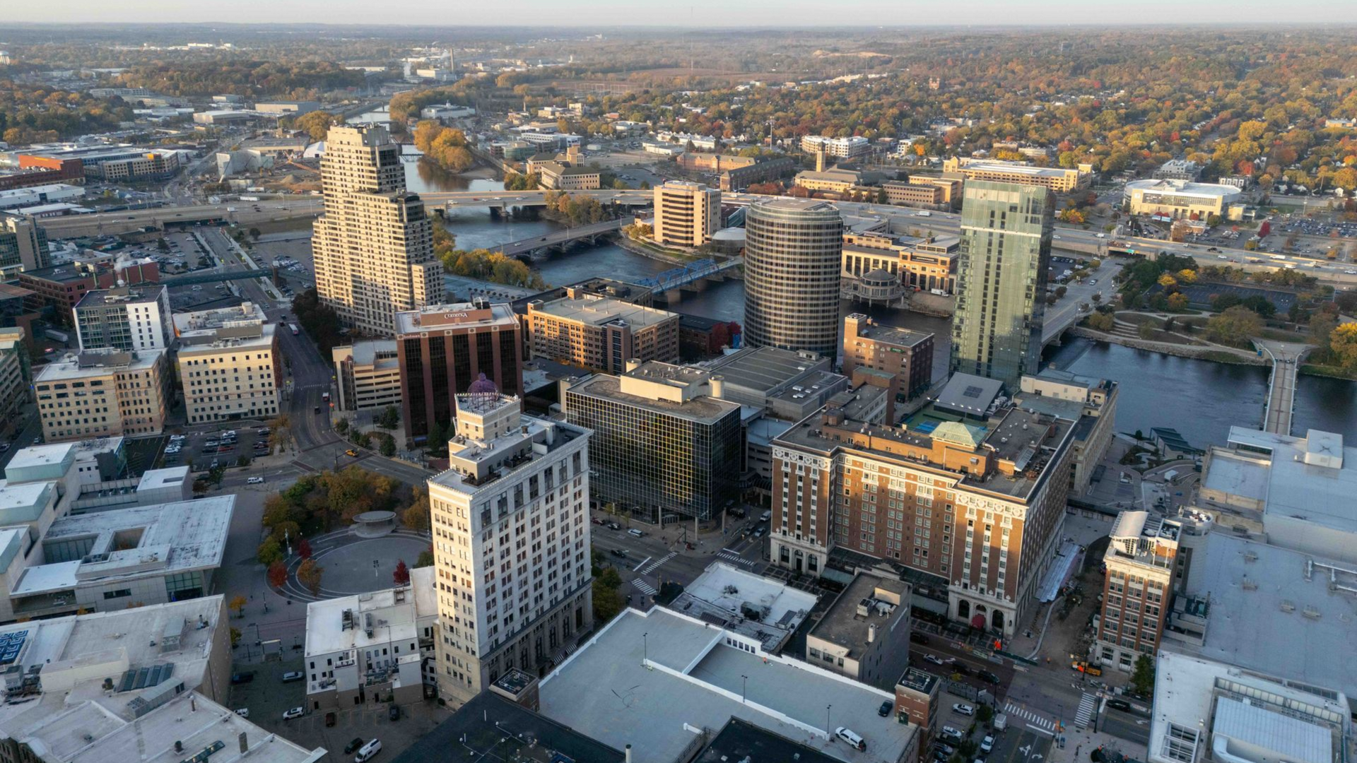 Aerial view of a downtown Grand Rapids, MI with buildings, streets, and a tall ornate tower at sunset.
