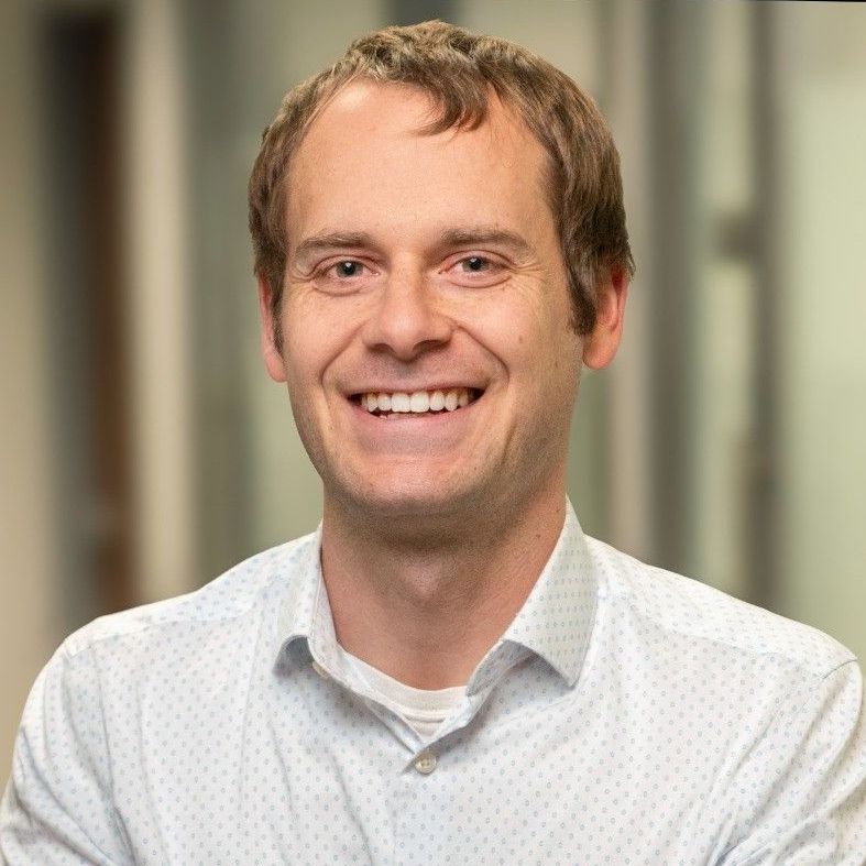 A man in a white shirt is smiling for the camera.