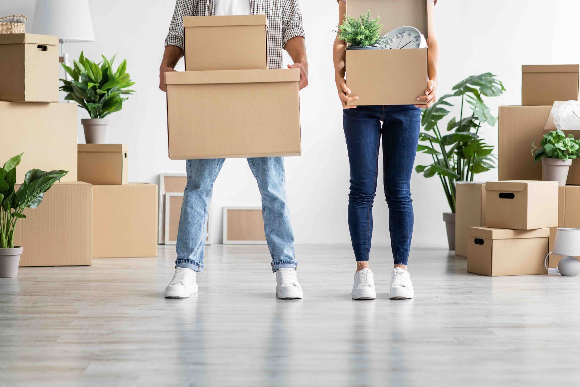 A man and a woman are holding cardboard boxes in a room filled with cardboard boxes.