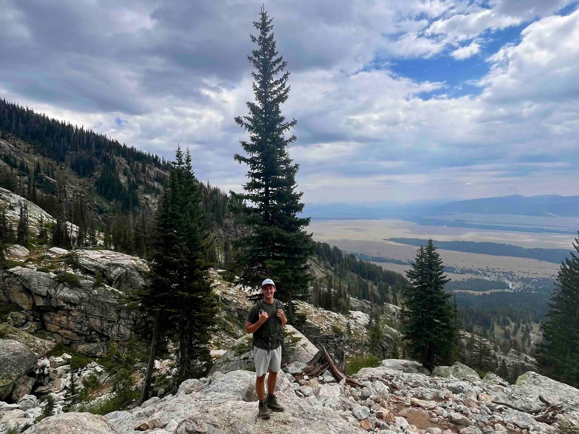 A man is standing on top of a rocky mountain.