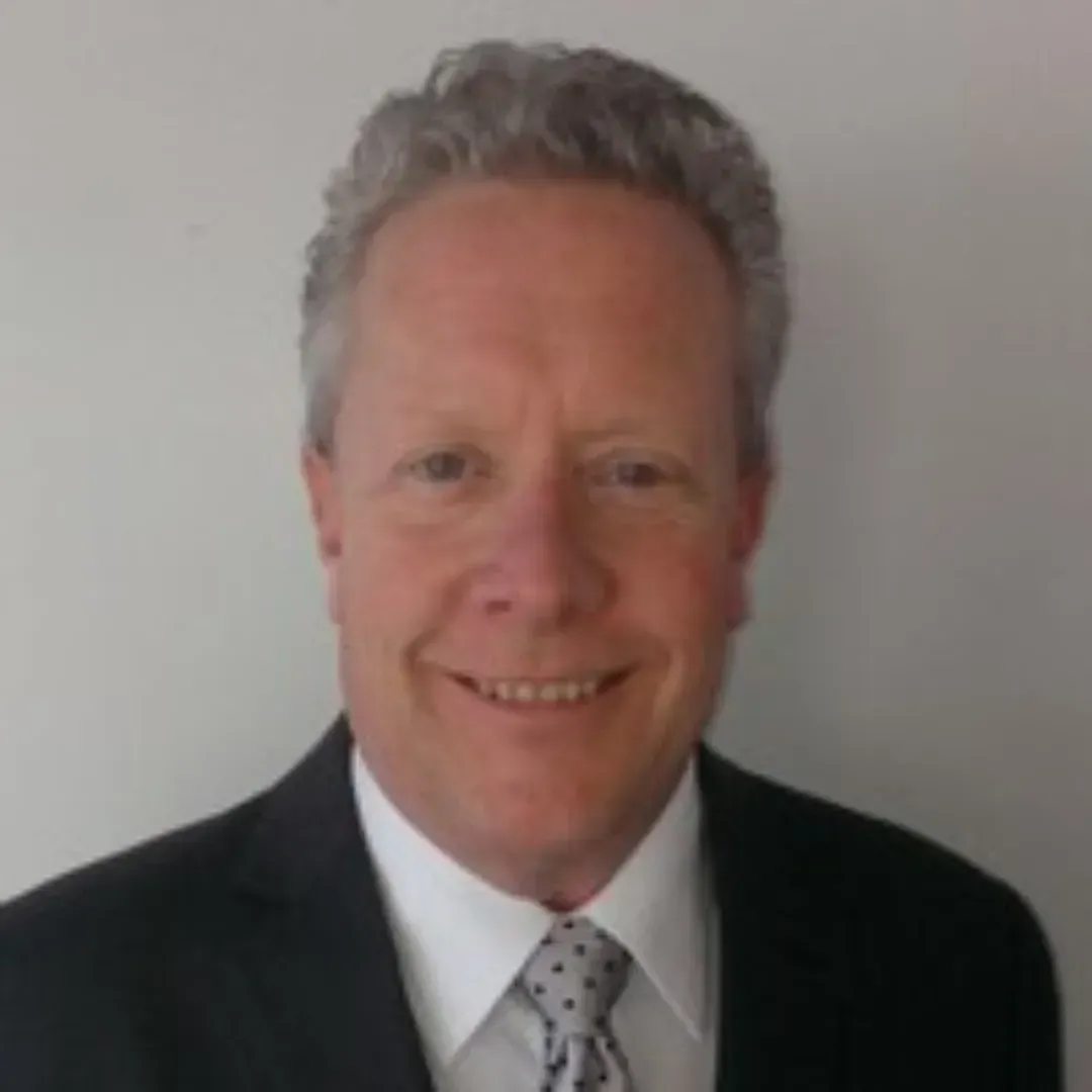 Larry Langton is wearing a suit and tie while smiling for the camera.