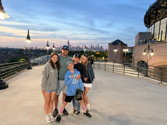 Kevin Lee and his family posing at dusk, with a city skyline and bridge in the background.