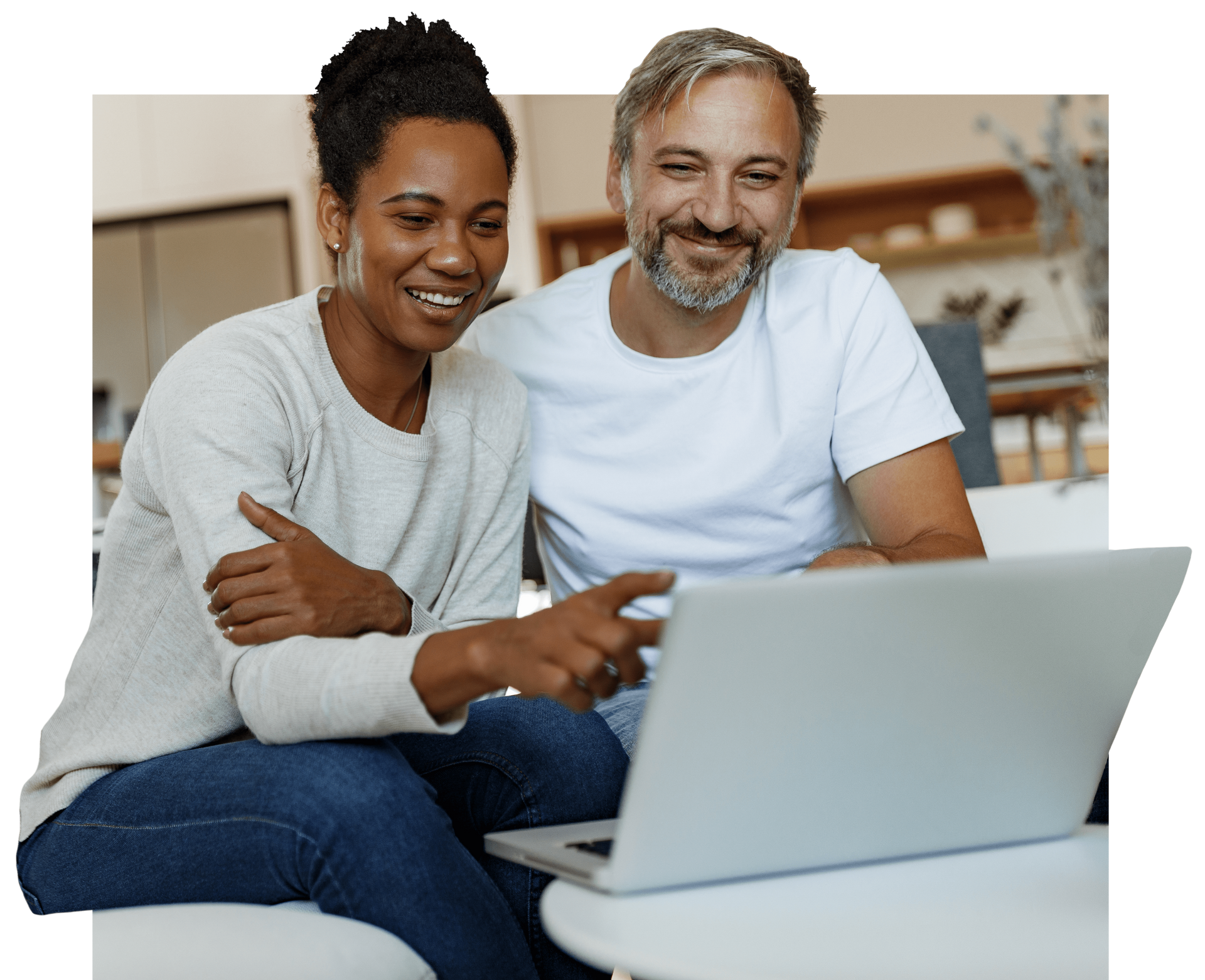 A man and a woman are sitting on a couch looking at a laptop computer.