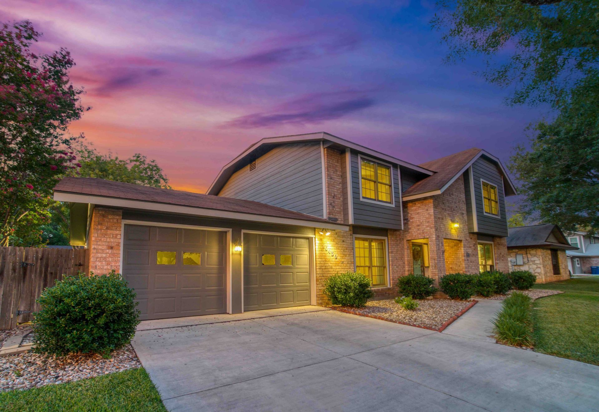 A large house with two garage doors and a sunset in the background
