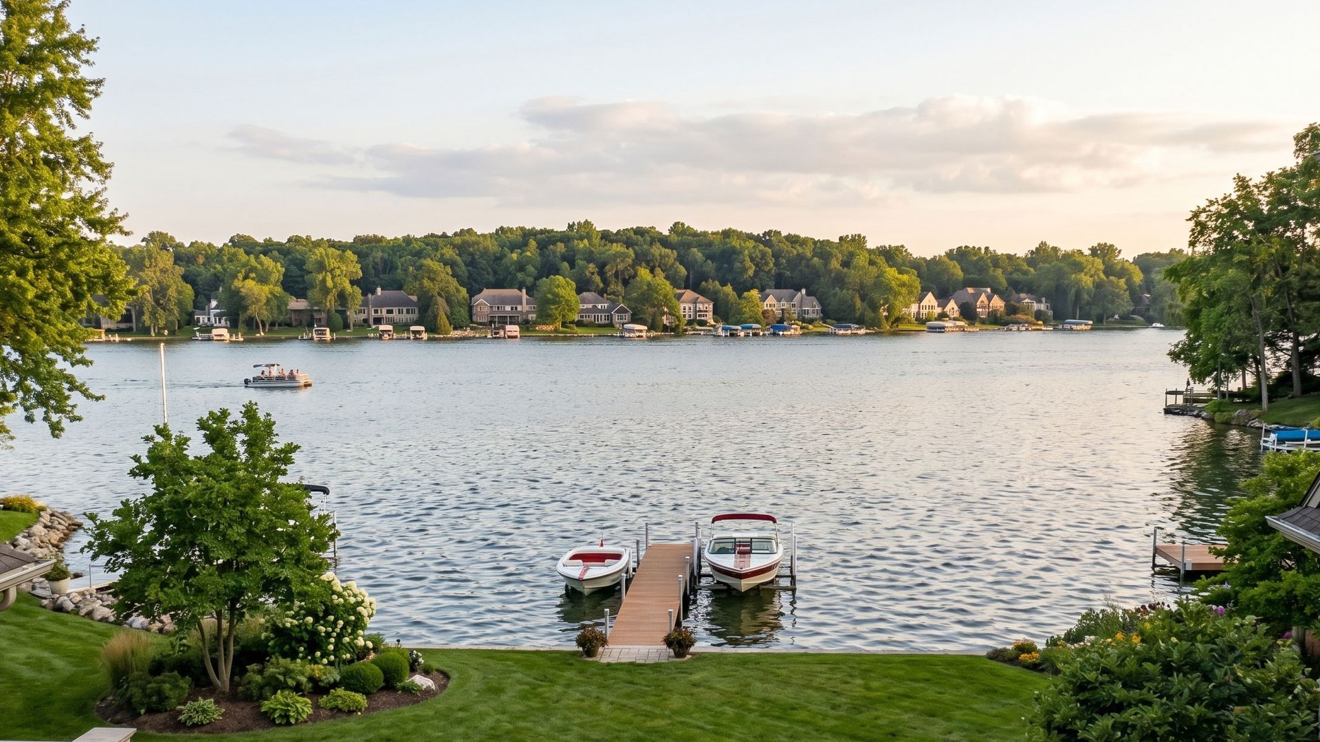 Lakeside view with docks, boats, and homes across calm water at sunset