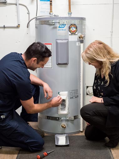 person writing on clipboard while in front of water heater