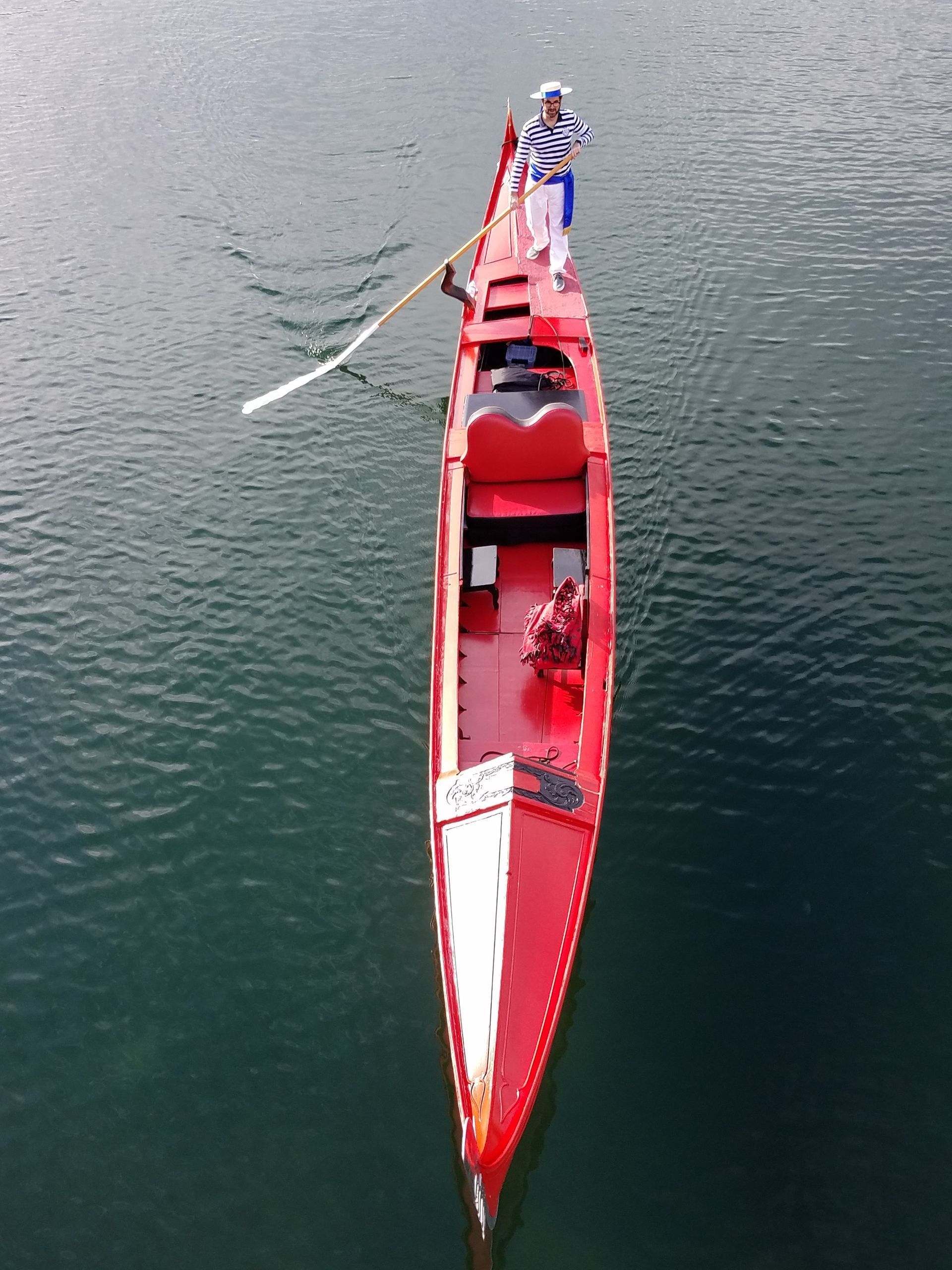 A man is rowing a red boat in the water
