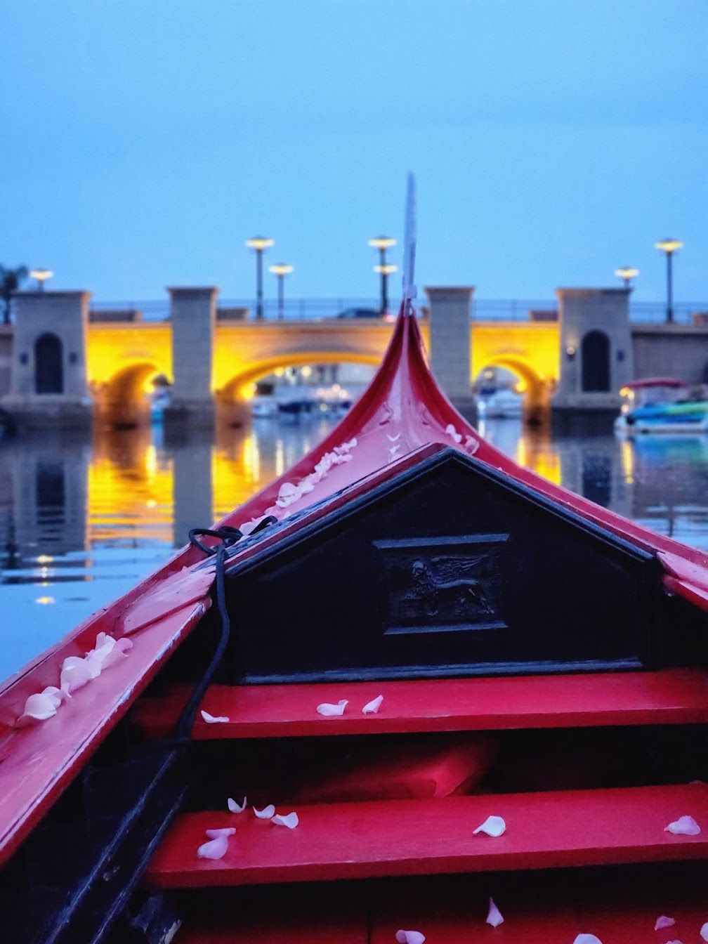 A red boat in the water with a bridge in the background
