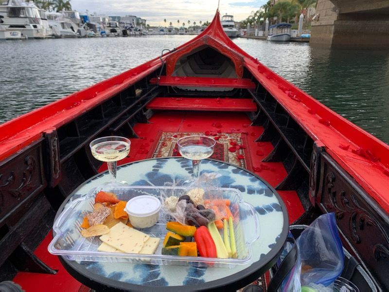 A table with a tray of food and two glasses of wine on it in the back of a boat.