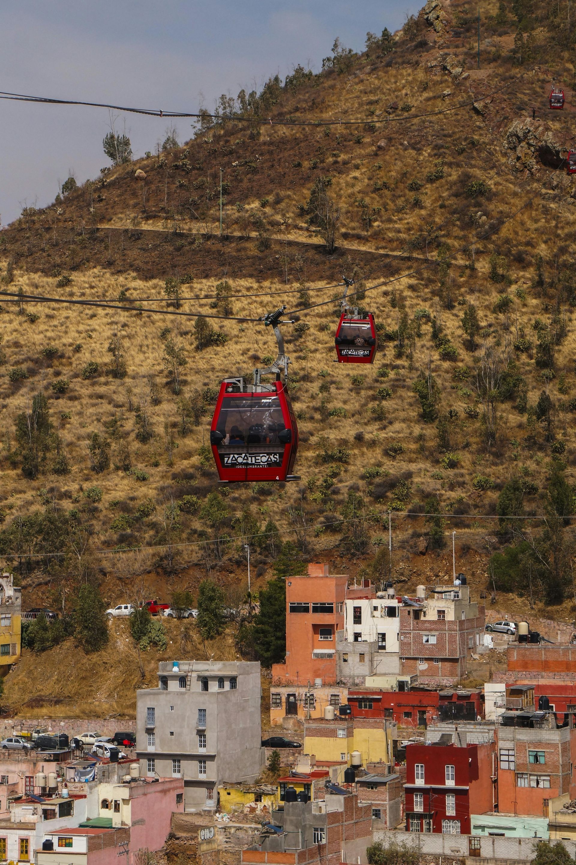 A cable car is going up a hill over a city.