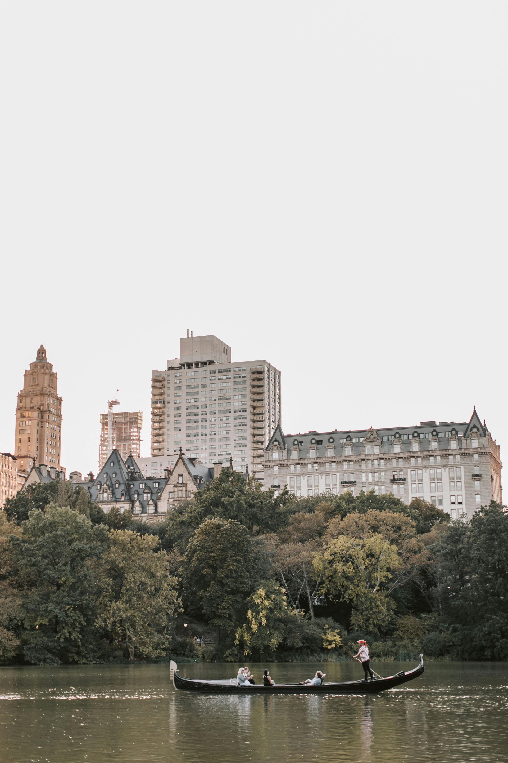A couple is riding a gondola on a lake in central park.