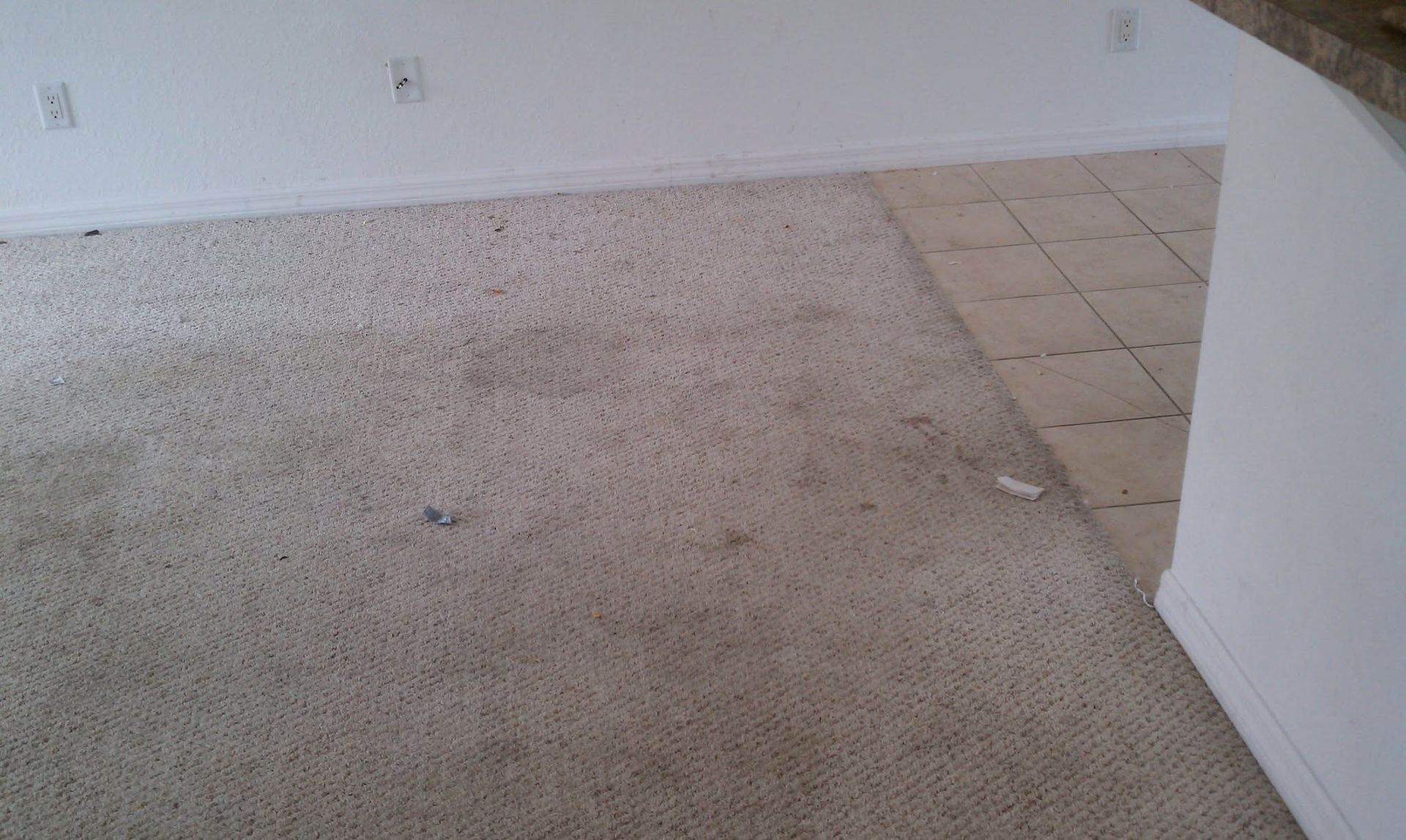 Empty carpeted room with a small section of beige tile flooring along the right wall.