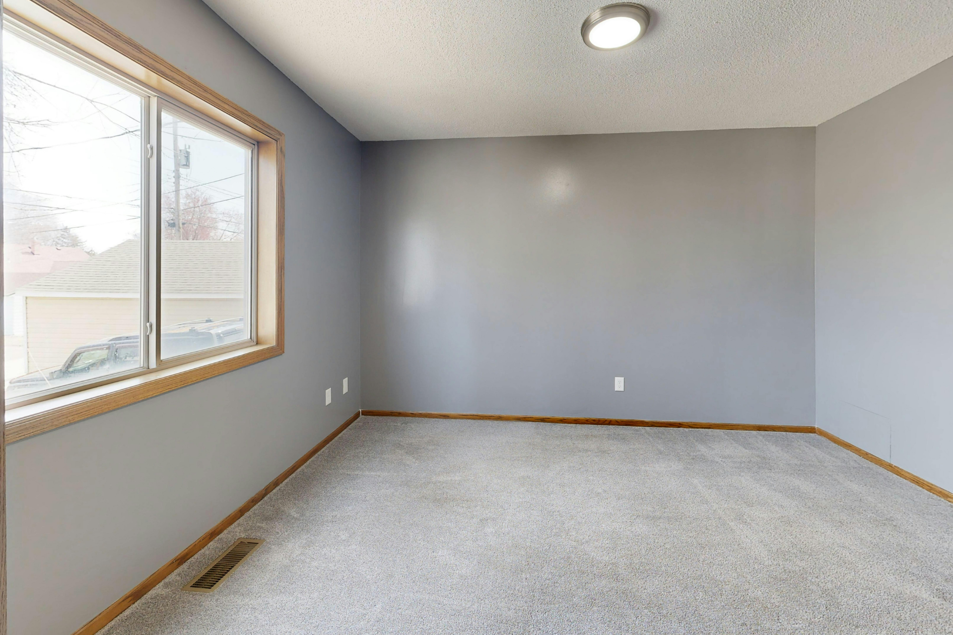 Empty gray bedroom with carpet, window, and ceiling light