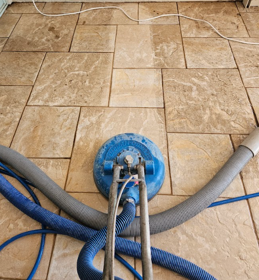 Blue carpet-cleaning machine on tan tile floor with hoses attached