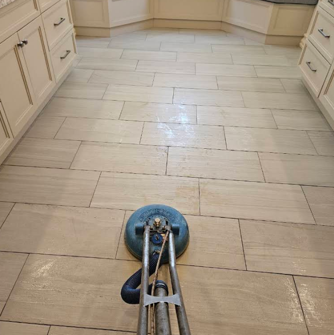 Blue floor-cleaning machine on a light tile kitchen floor between cabinets