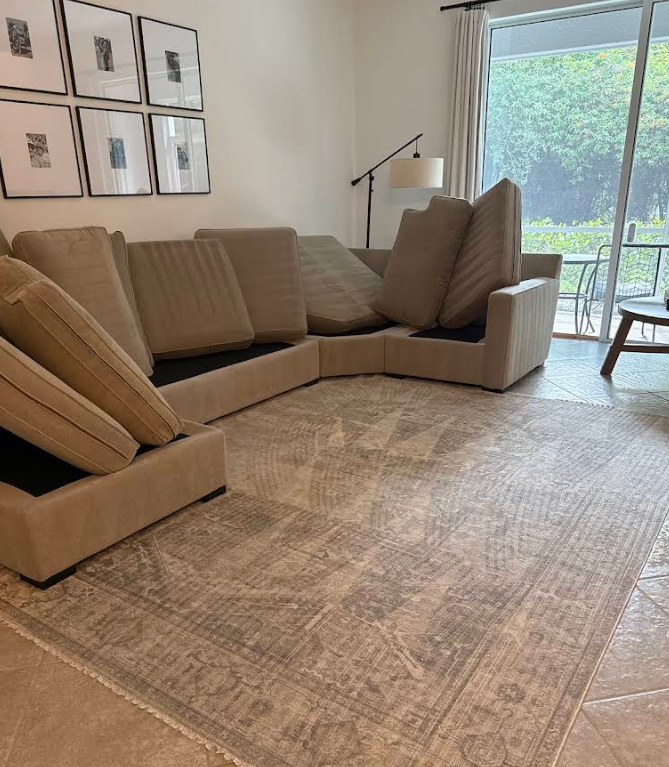 Sectional sofa in a bright living room beside a large window and neutral rug.