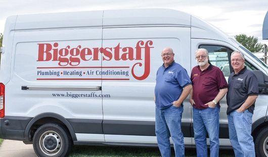 Biggerstaff plumbing and HVAC service van with three men standing beside it