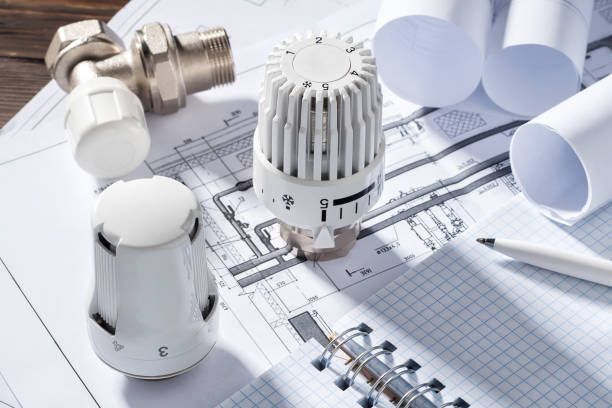 Heating valves and radiator thermostats on architectural blueprints with rolled plans