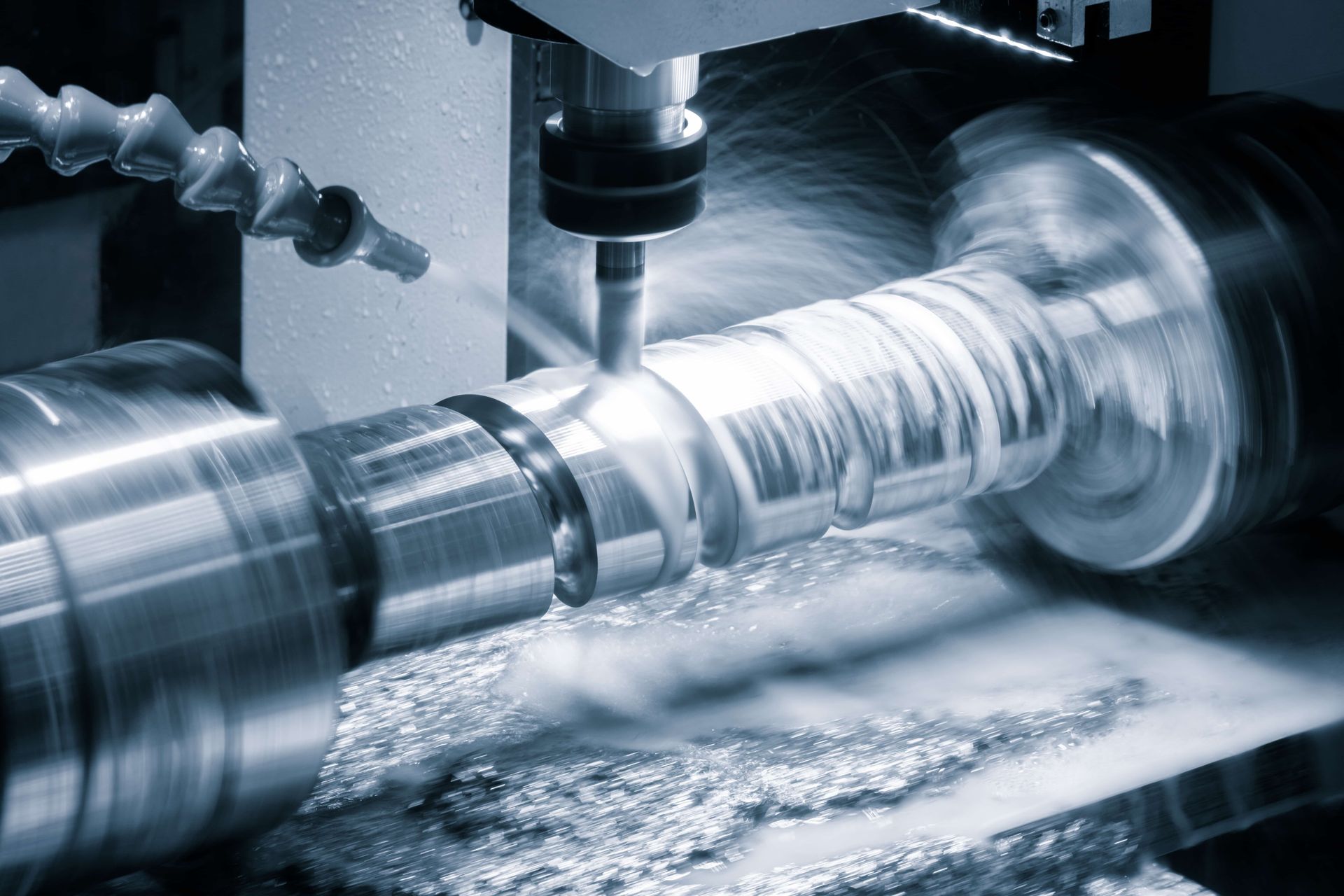 CNC machine cutting metal cylindrical part, coolant spraying.