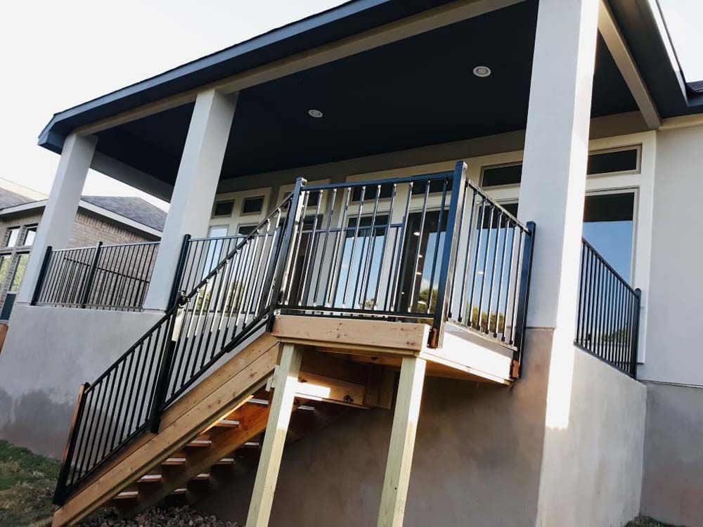 Deck with black railings, wooden stairs, and a covered patio area.
