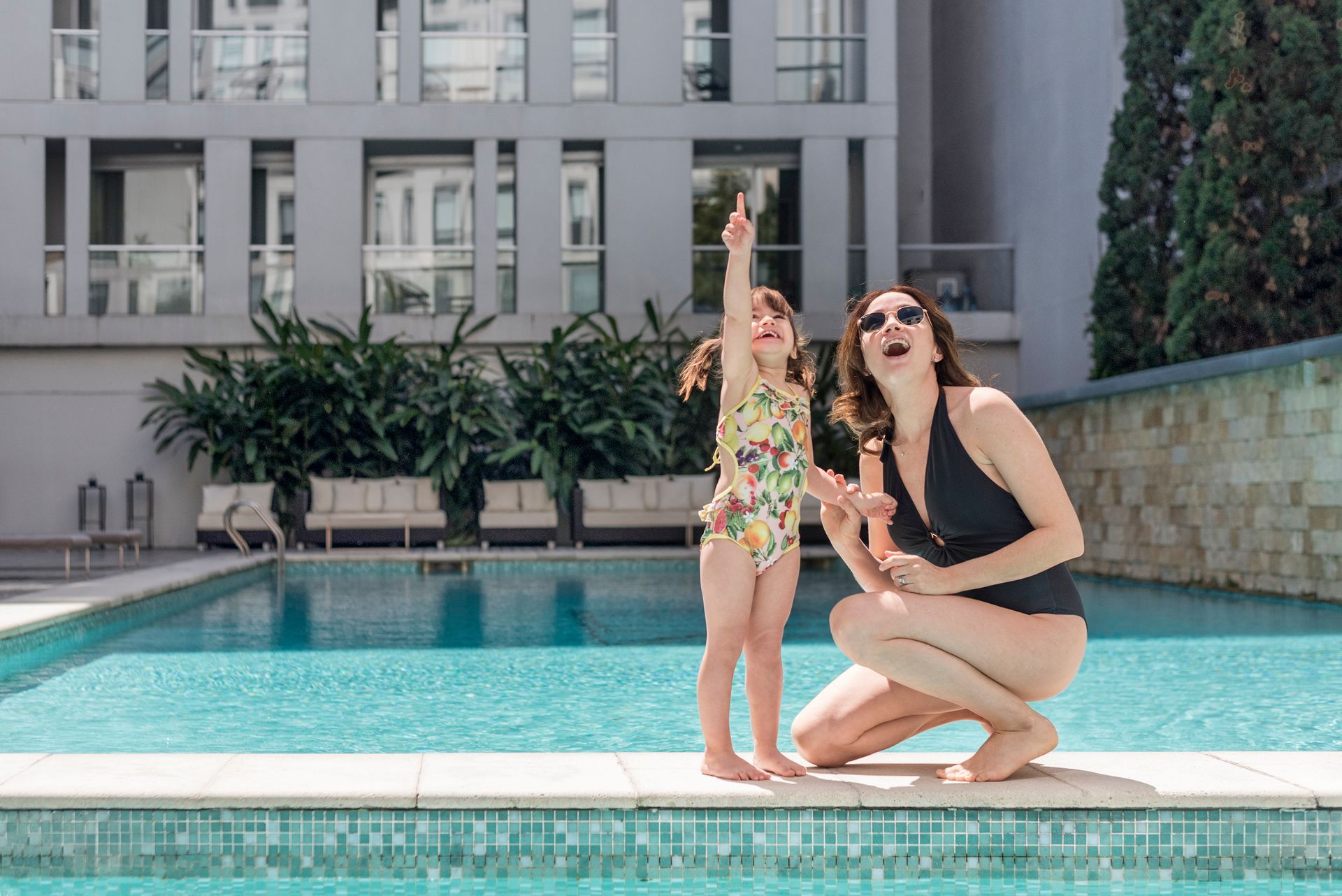 Una mujer y una niña están arrodilladas junto a una piscina.