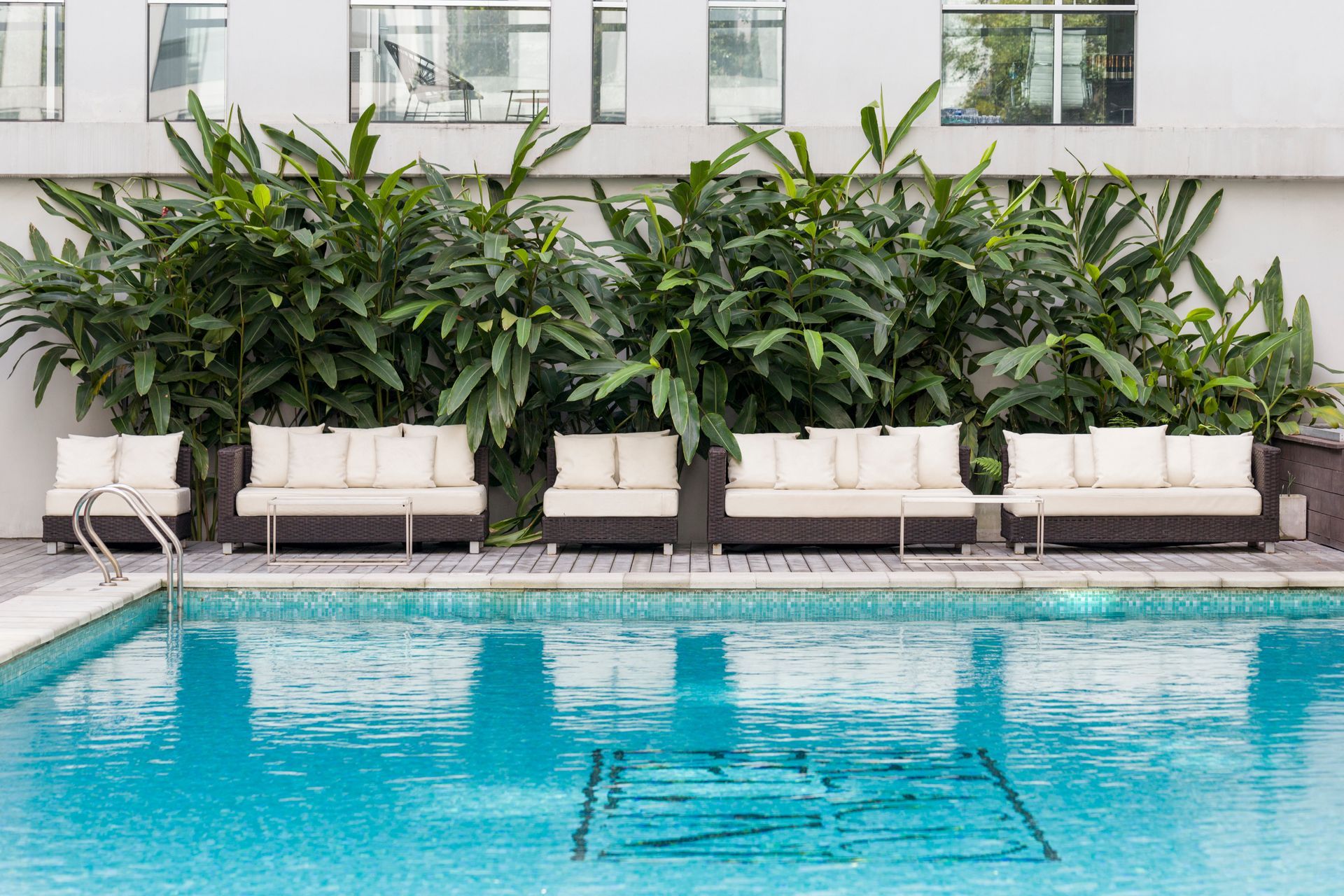 Una gran piscina rodeada de plantas y sofás.