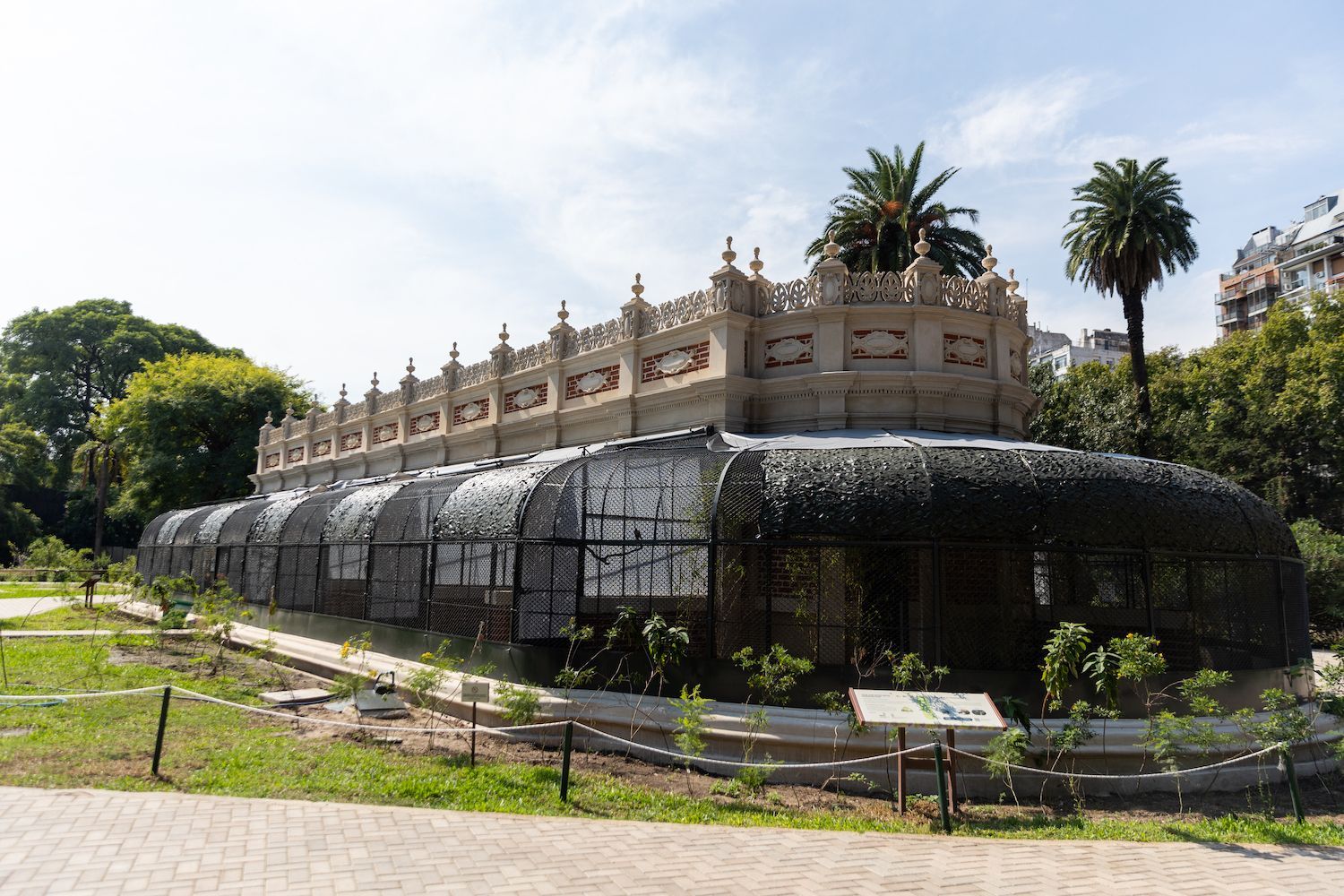 Un edificio grande con muchas ventanas está rodeado de árboles y césped.
