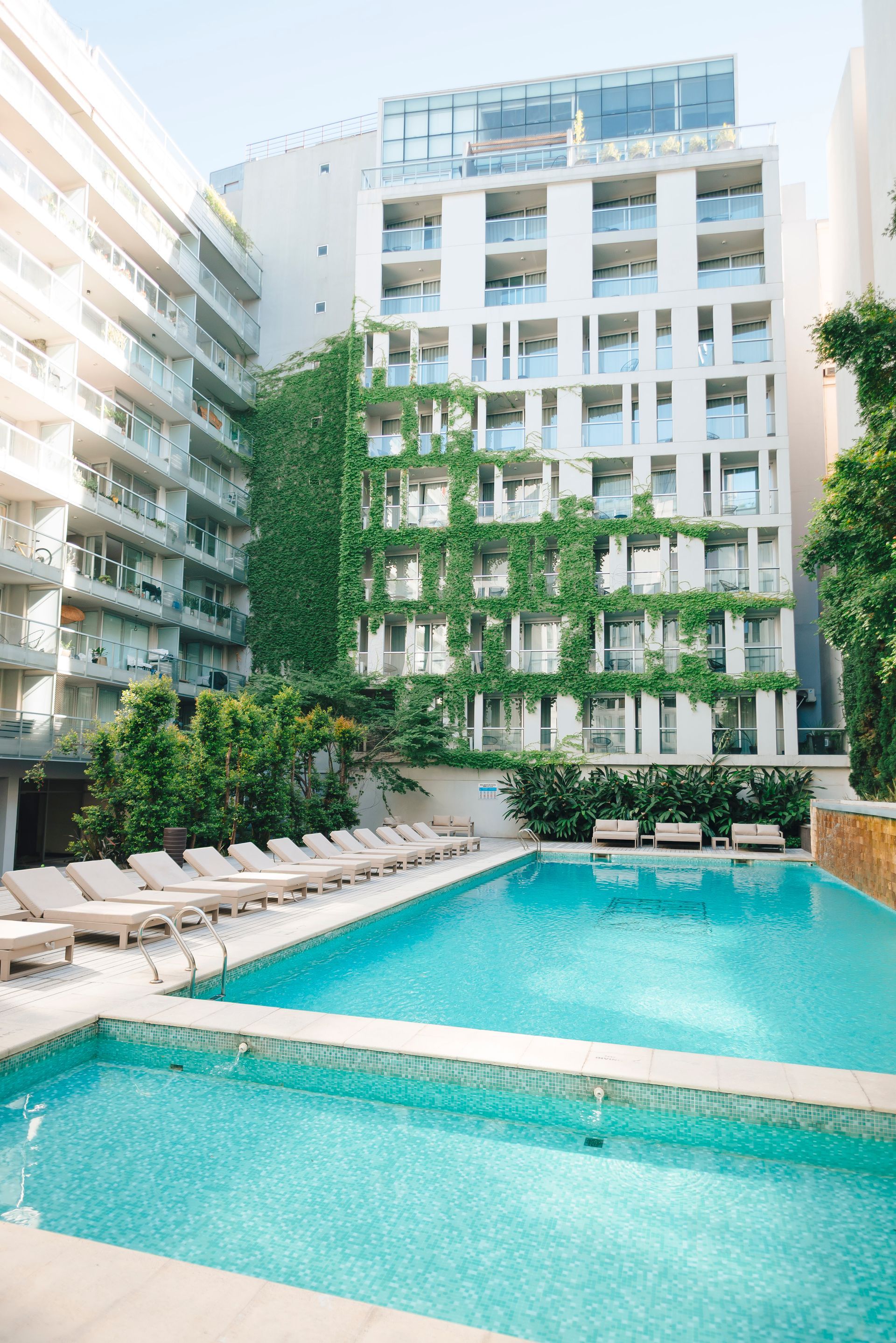 Una gran piscina rodeada de plantas y sofás.