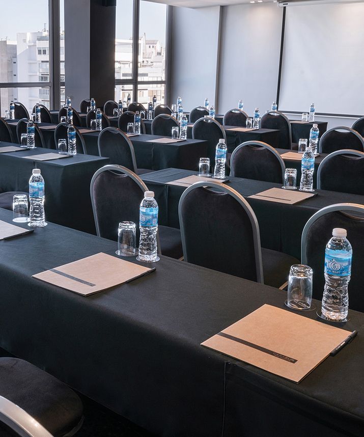 una sala de conferencias con mesas y sillas preparadas para una reunión