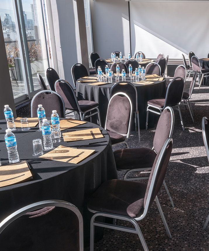 Una sala con mesas y sillas preparadas para una reunión.