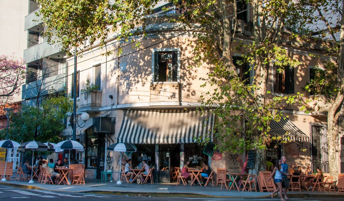 Un grupo de personas están sentadas en mesas afuera de un restaurante.