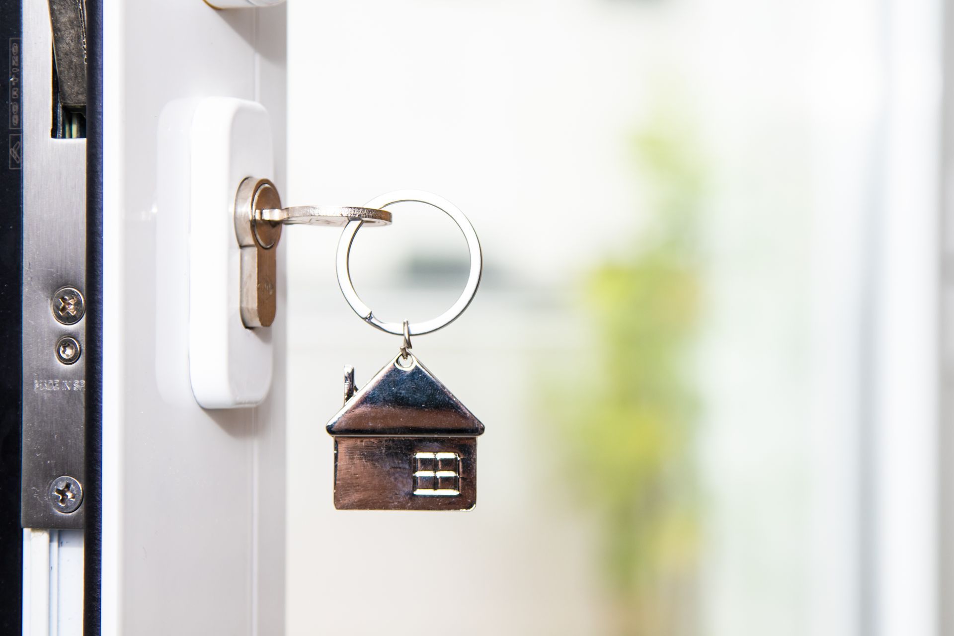 A key with a house design inserted into the keyhole of a door, symbolizing locksmith services for residential properties