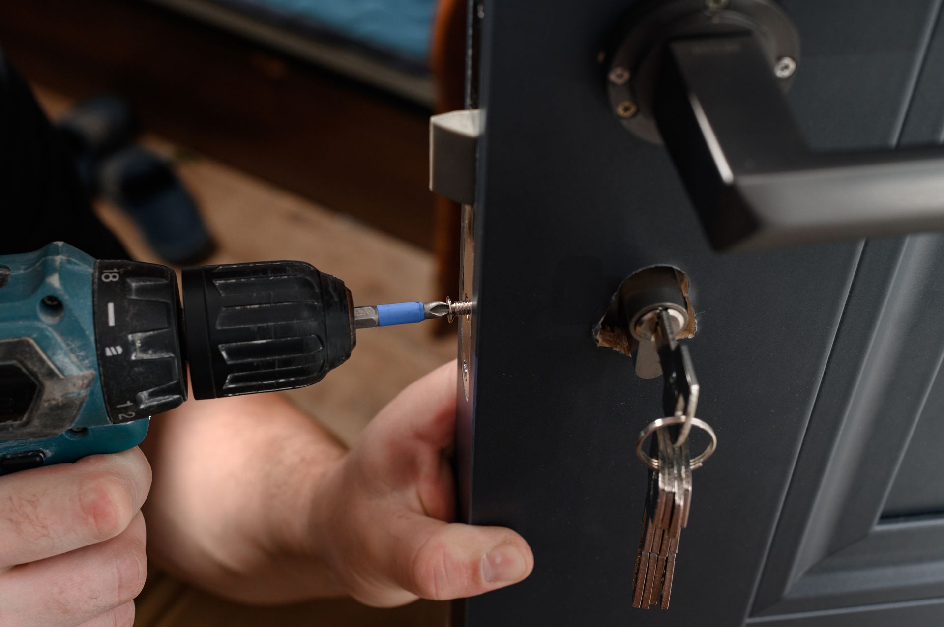 Skilled locksmith performing a precision drill on the side of a door to install a secure lock.
