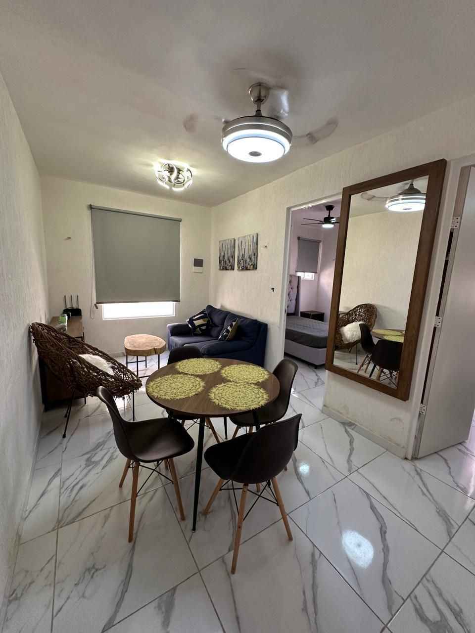 Salón moderno con suelo de mármol, mesa redonda, sillas, sofá, lámpara y espejo de pared.