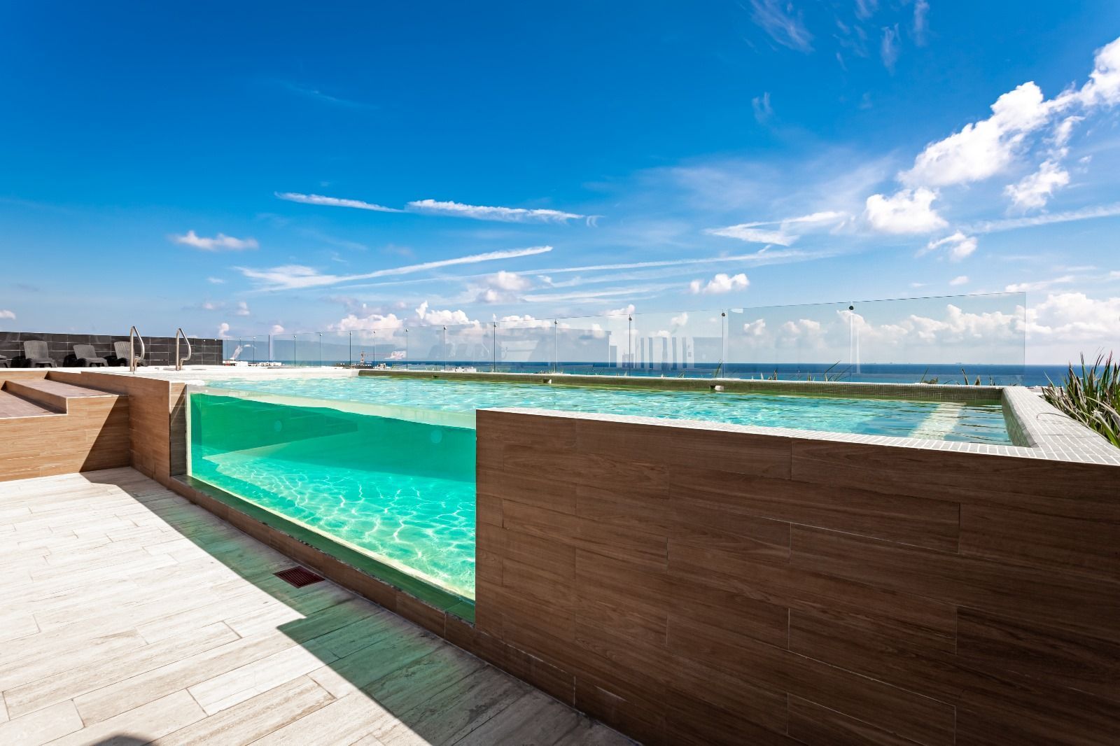 Moderna piscina infinita con agua turquesa con vistas al océano bajo un cielo azul brillante.