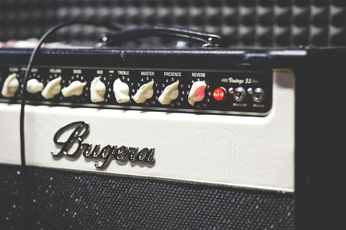 Close-up of a white Bugera Vintage 55 guitar amplifier with black knobs and red power light.