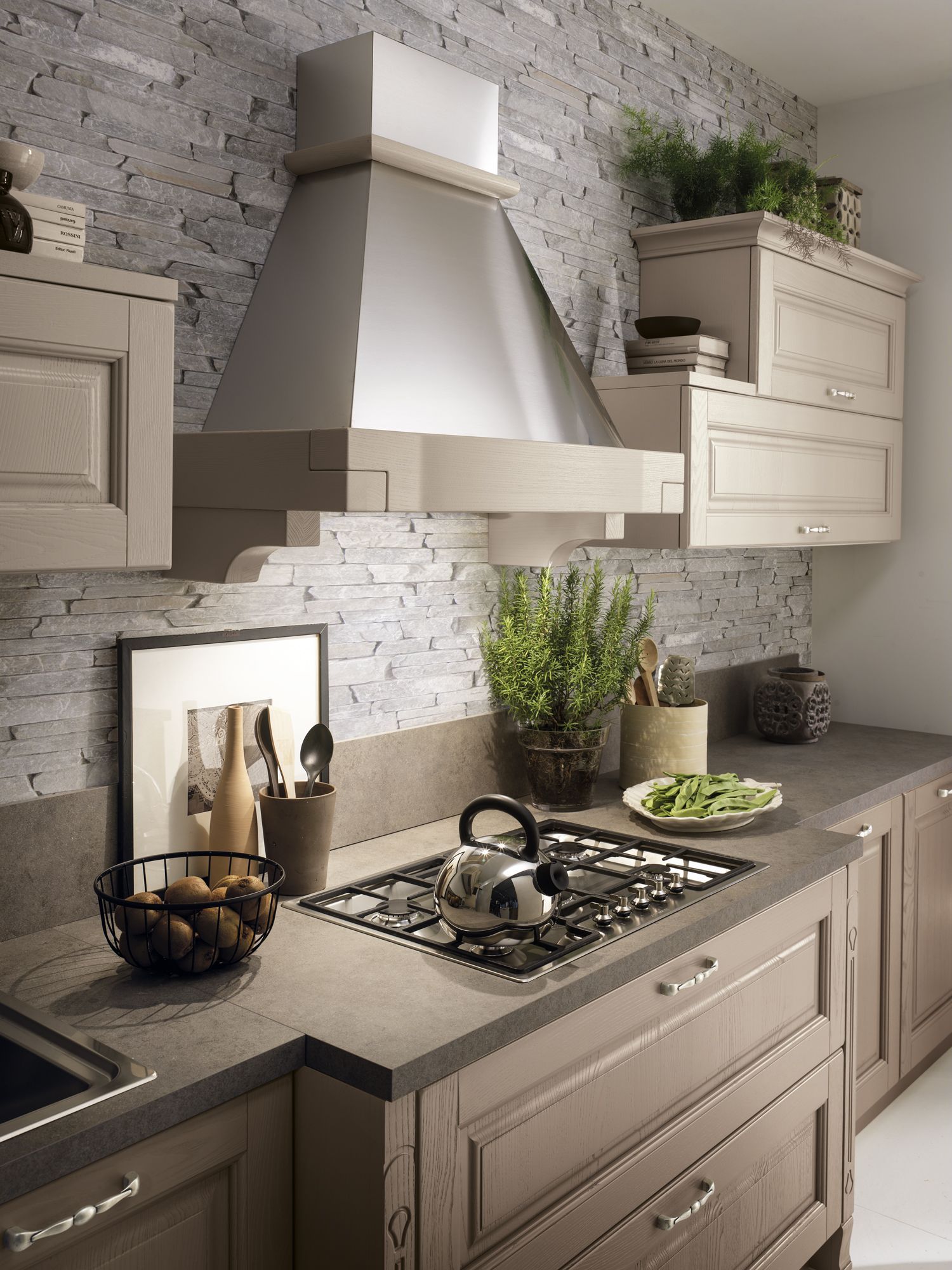 Cucina con paraschizzi in pietra, cappa in acciaio inox e mobili marrone chiaro.