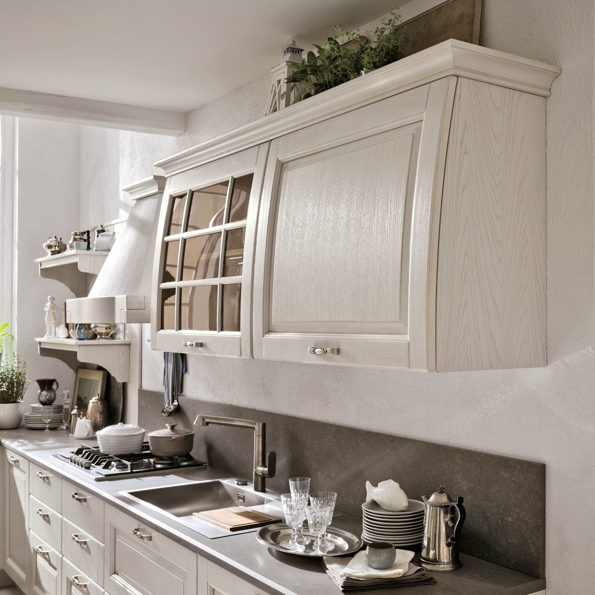 Cucina con mobili, lavello, piano di lavoro e fornelli dai colori chiari.