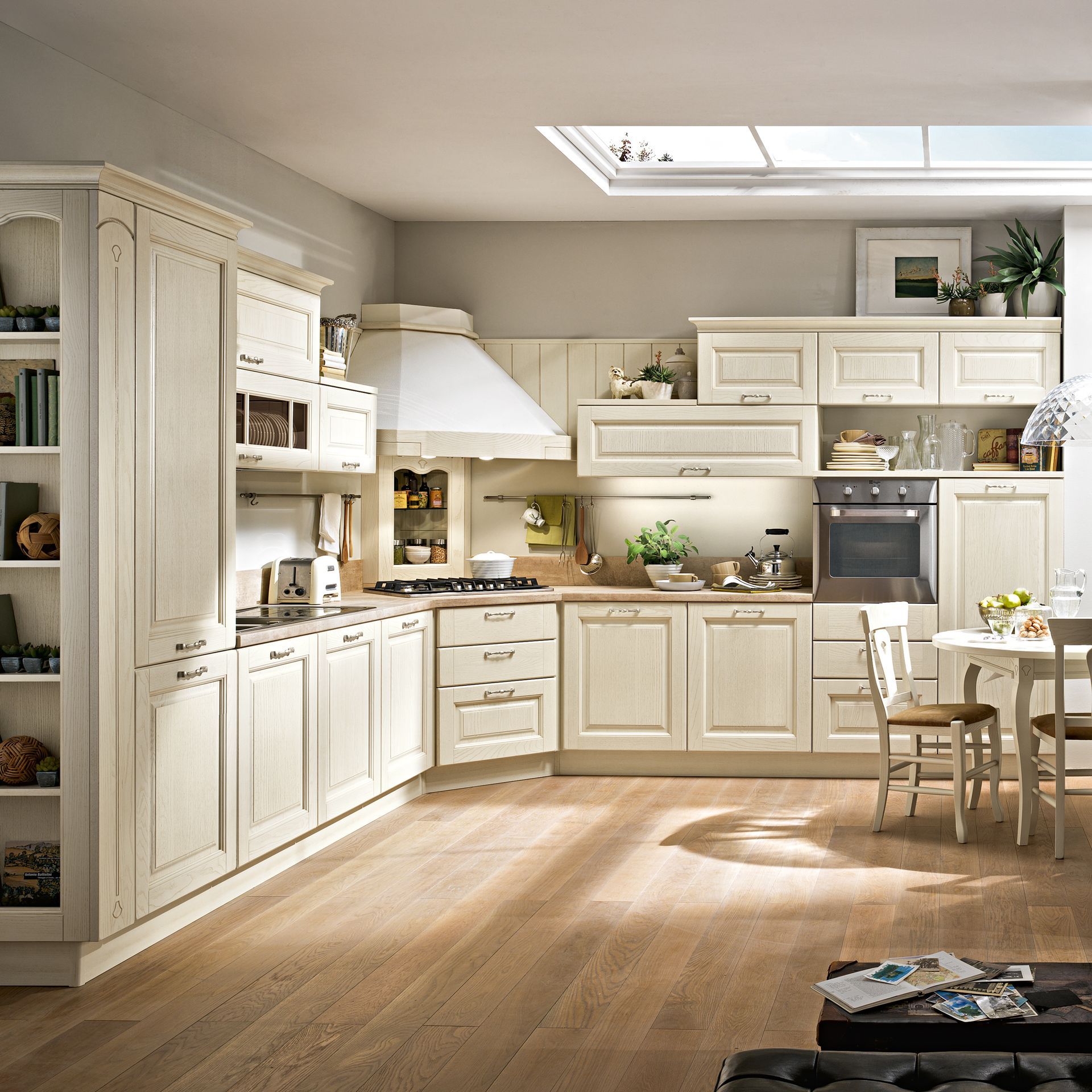 Cucina color crema con pavimenti in legno, mobili e tavolo da pranzo. La luce del sole filtra attraverso un lucernario.