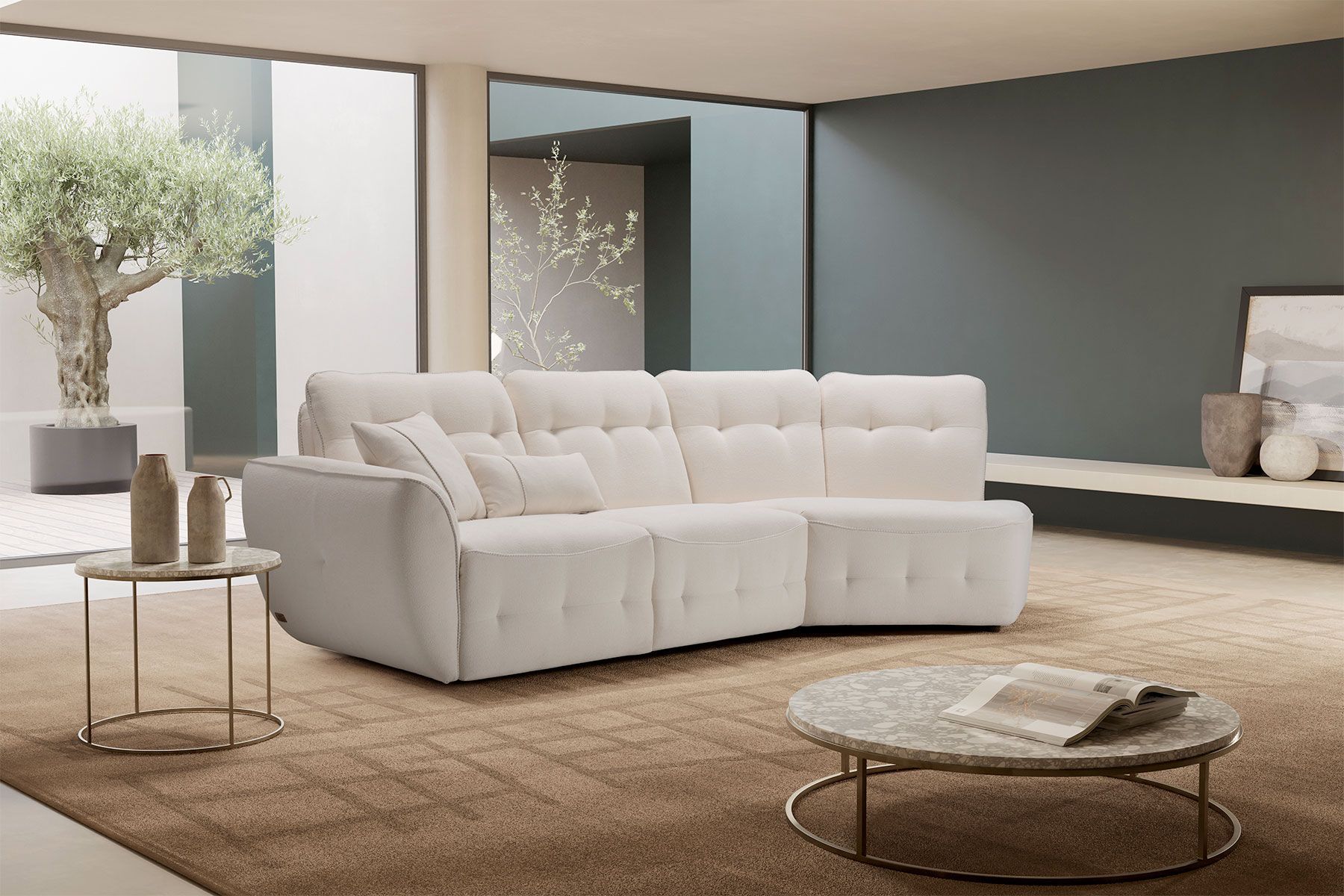 Divano componibile beige in un soggiorno moderno con un tappeto e due tavoli circolari.