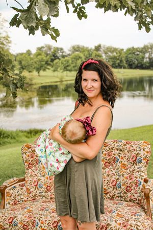 A woman is holding a baby in her arms while sitting on a couch.