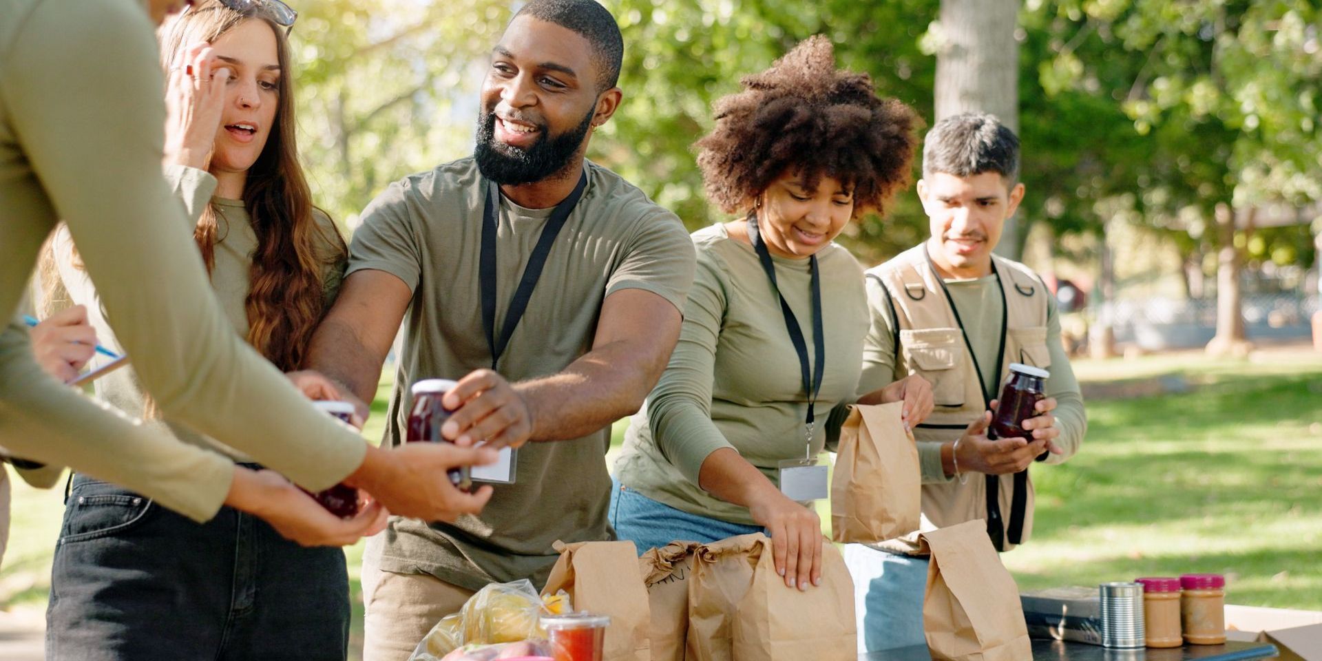 A group of people are standing around a table in a park.