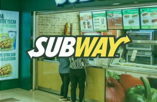 A couple of people standing in front of a subway restaurant.