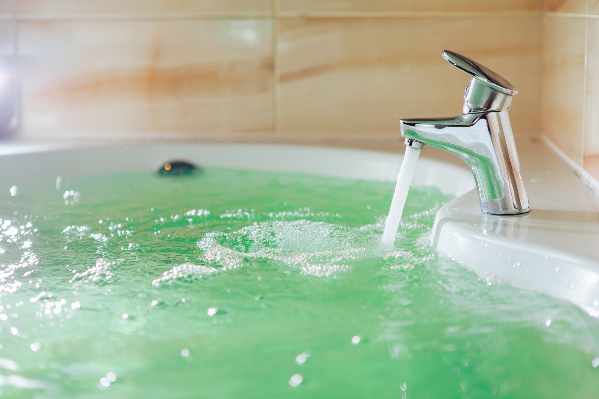 Bathtub filled with green water; faucet pouring water.