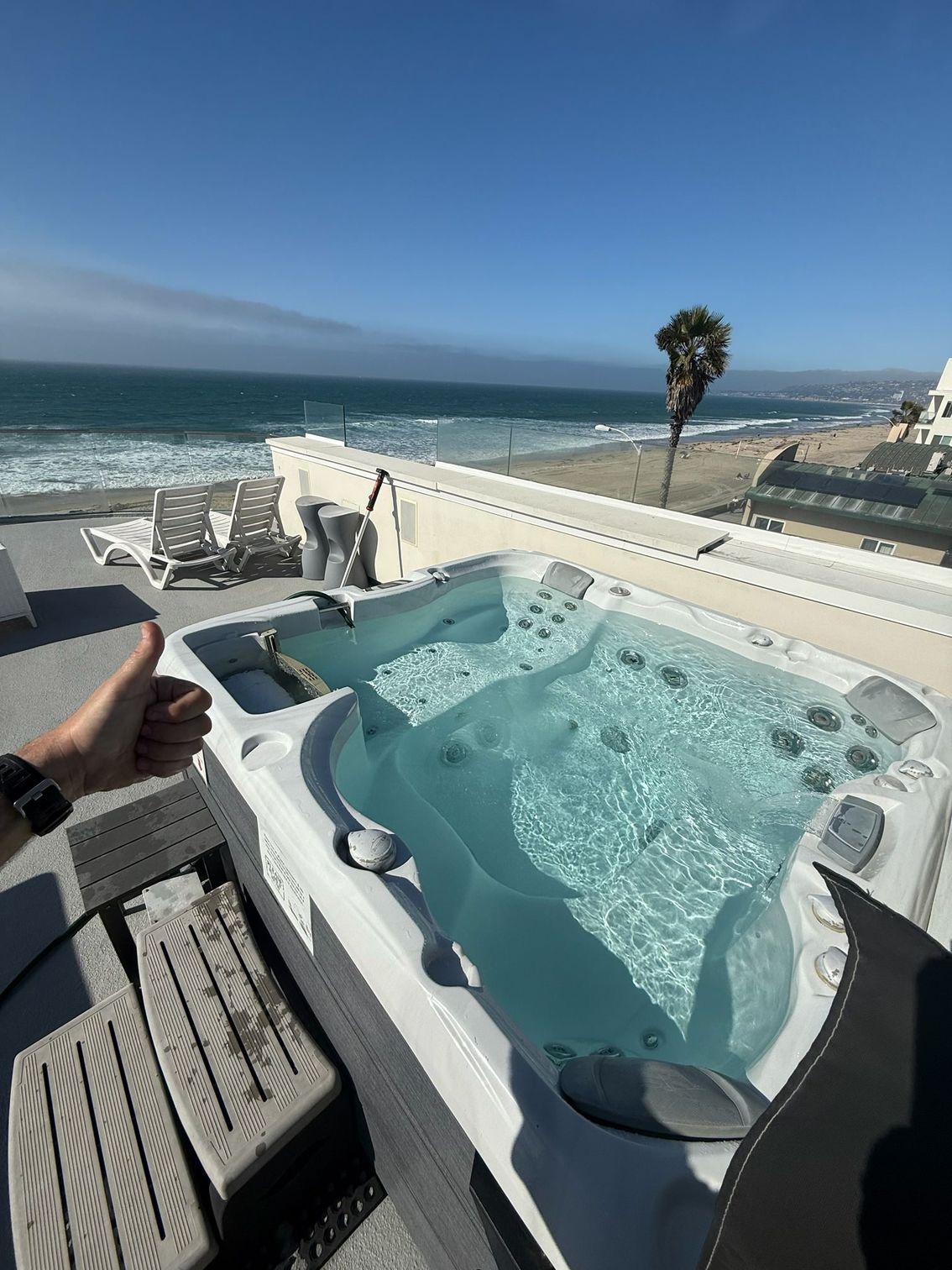 Two women relax in a bubbling hot tub; one smiles, water splashes around them.