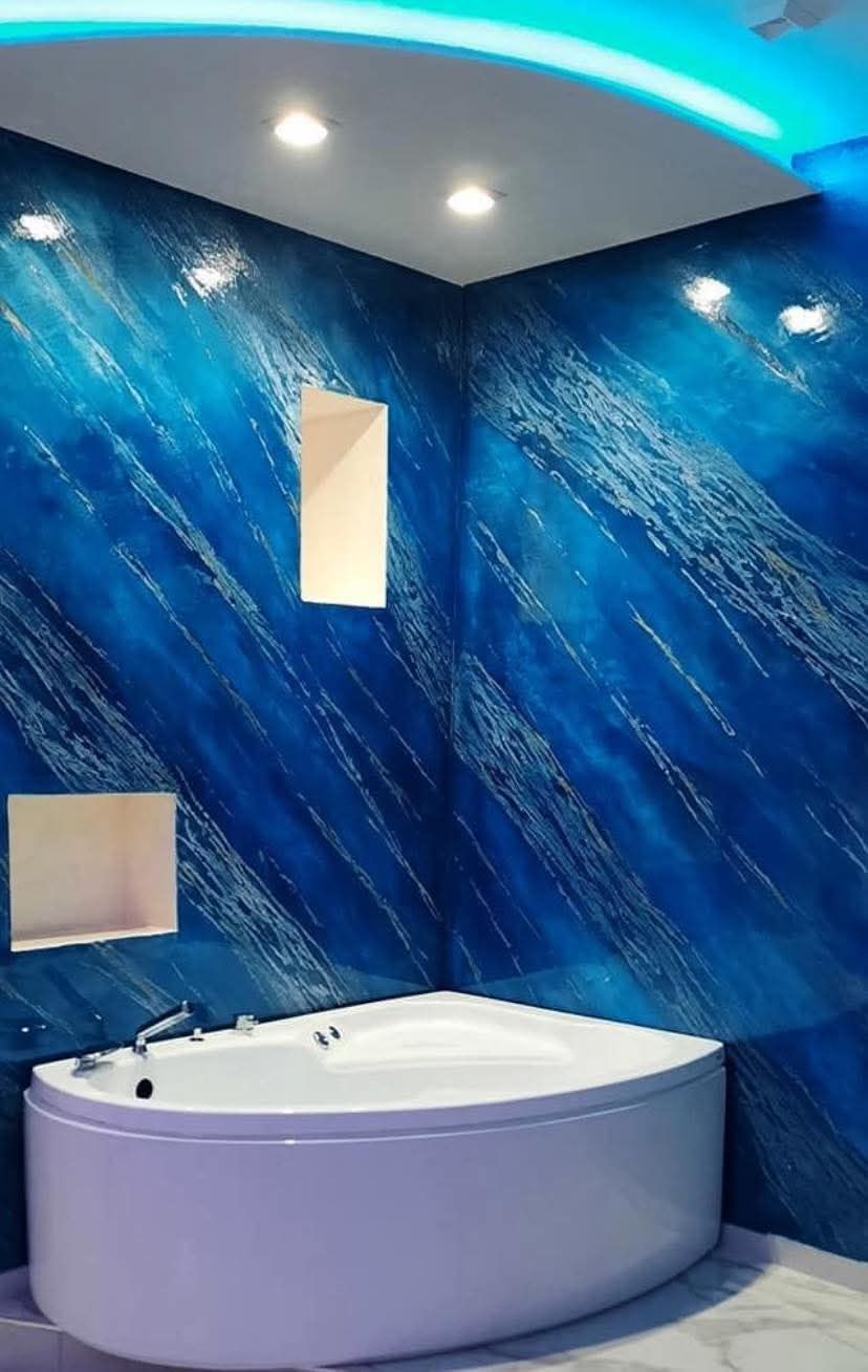 Bagno moderno con pareti blu texturizzate, vasca da bagno bianca curva e plafoniera a LED blu.