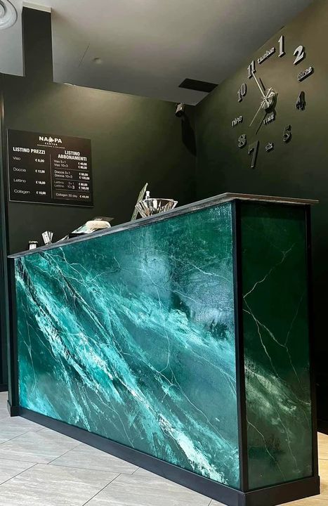 Banco reception moderno con motivo in marmo color verde acqua in un atrio interno scuro